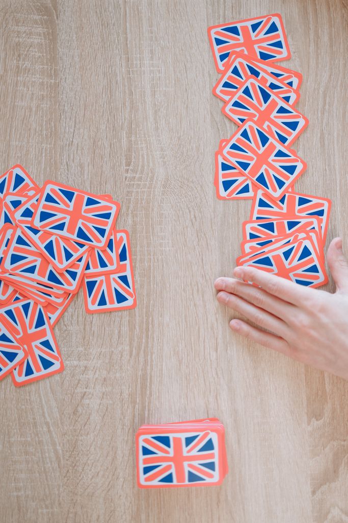 A hand arranging Union Jack flag cards on a wooden surface, perfect for gaming concepts.