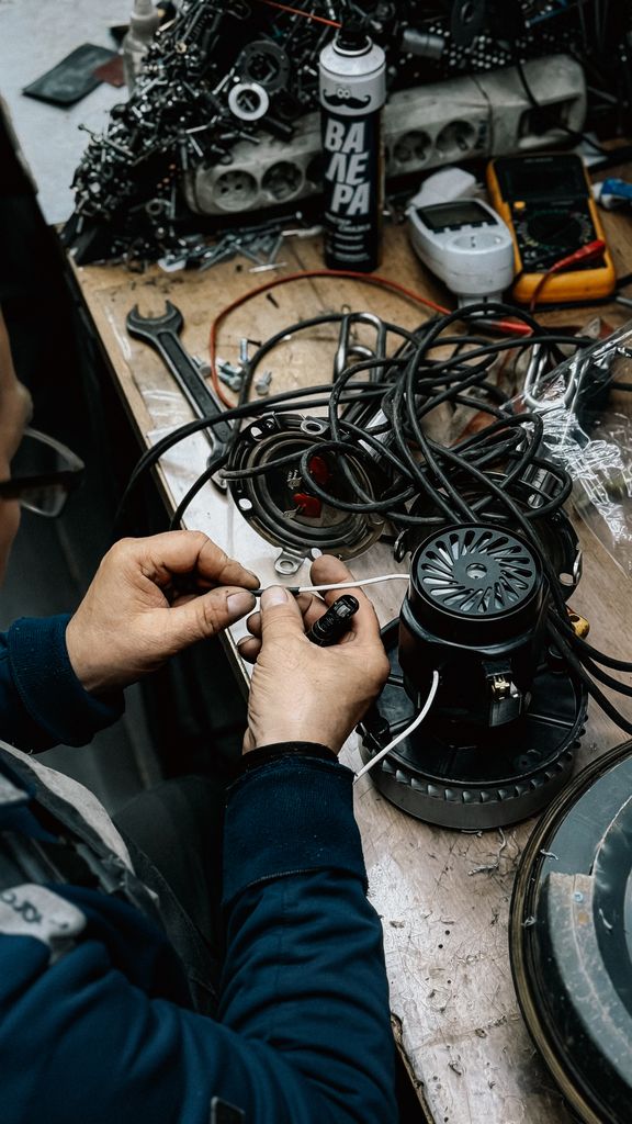 An adult technician working on repairing electrical equipment in a workshop setting.